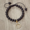 A handmade beaded bracelet featuring natural black stones and a gold zodiac charm.