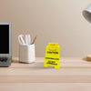 A yellow caution desk sign with text warning against approaching due to overstimulation sits on a wooden desk.
