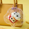 A clear plastic pouch containing a white and red collectible squeeze toy keychain attached to a tan leather handbag.