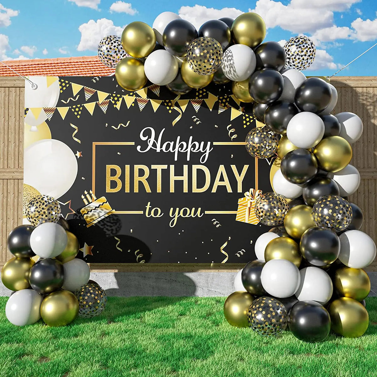 A balloon garland arch featuring black, gold, and white balloons with starburst accents set against a dark backdrop.