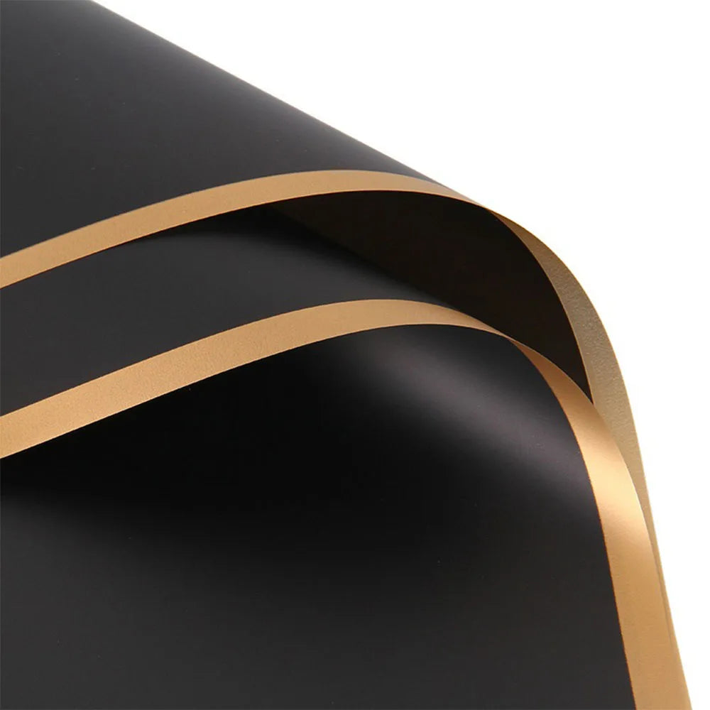 Close-up of black wrapping paper with a gold edge design and a curved fold.
