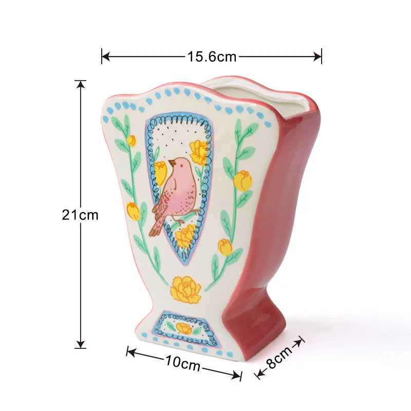 A pink ceramic vase shaped like a bird, decorated with floral patterns and blue accents.