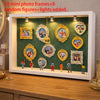 Weiße Displaybox mit zehn Mini-Fotoframes und acht zufälligen Figuren mit Lichtern drinnen.