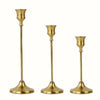 A set of three ornate vintage brass metal candle holders with flared bases.