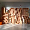 Wooden alphabet letters spelling LOVE STAY mounted on a wall with small animal figures
