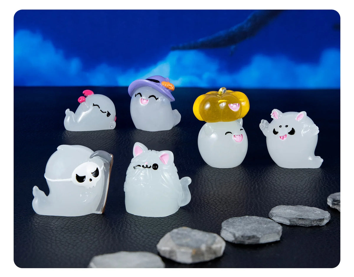 A set of seven cute luminous ghost resin ornaments in various shapes and colors against a dark background.
