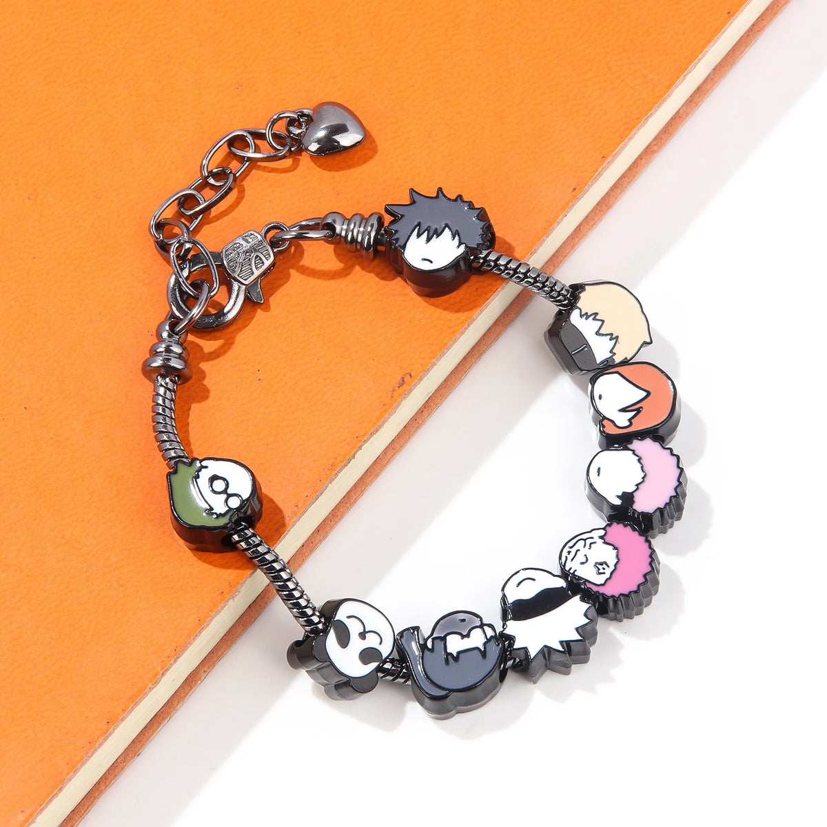 A silver charm bracelet featuring figures of Itadori, Fushiguro, and Gojo from Jujutsu Kaisen set against an orange backgroun