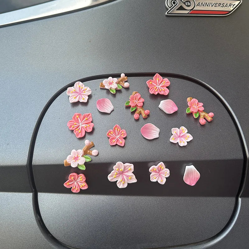 A collection of pink and orange 3D peach blossom flowers arranged on a dark car dashboard.