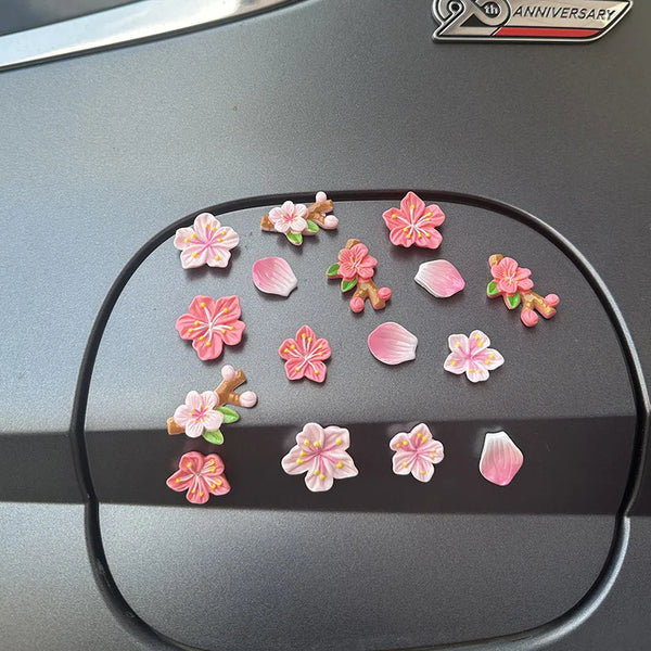 A collection of pink and orange 3D peach blossom flowers arranged on a dark car dashboard.
