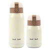 A white vacuum insulated coffee mug with a beige lid and a 'Good Luck' inscription.