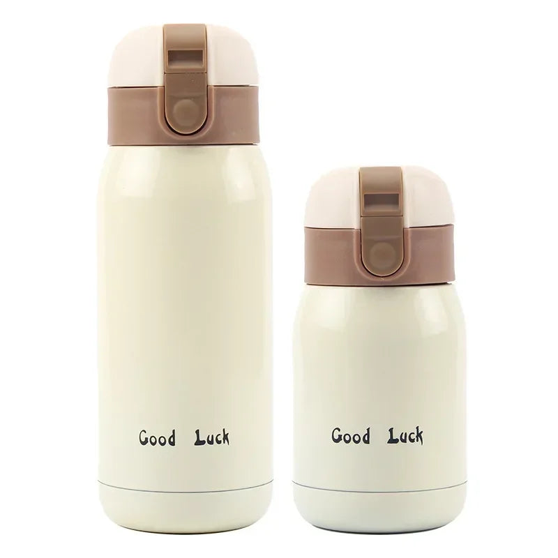 A white vacuum insulated coffee mug with a beige lid and a 'Good Luck' inscription.
