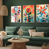Three canvas prints featuring colorful retro wildflowers and landscape designs displayed on a dark green wall.