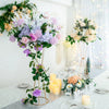 Gold geometric flower stands with purple and pink flowers decorating a table.