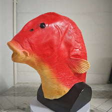 A realistic red and yellow fish head latex mask displayed on a black stand.