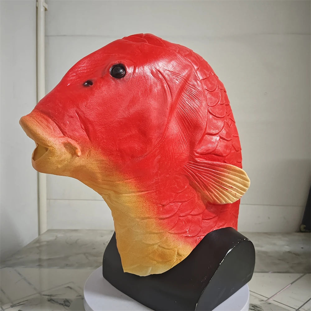 A realistic red and yellow fish head latex mask displayed on a black stand.