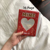 A red photo album titled MINE with a heart design is held in a hand on white bedding.
