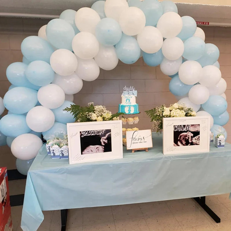 Arche de ballons bleu clair et blanc avec des photos encadrées sur une table.