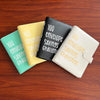A set of four colored envelopes and a binder organizer for the 100 Envelope Savings Challenge displayed on a wooden surface.