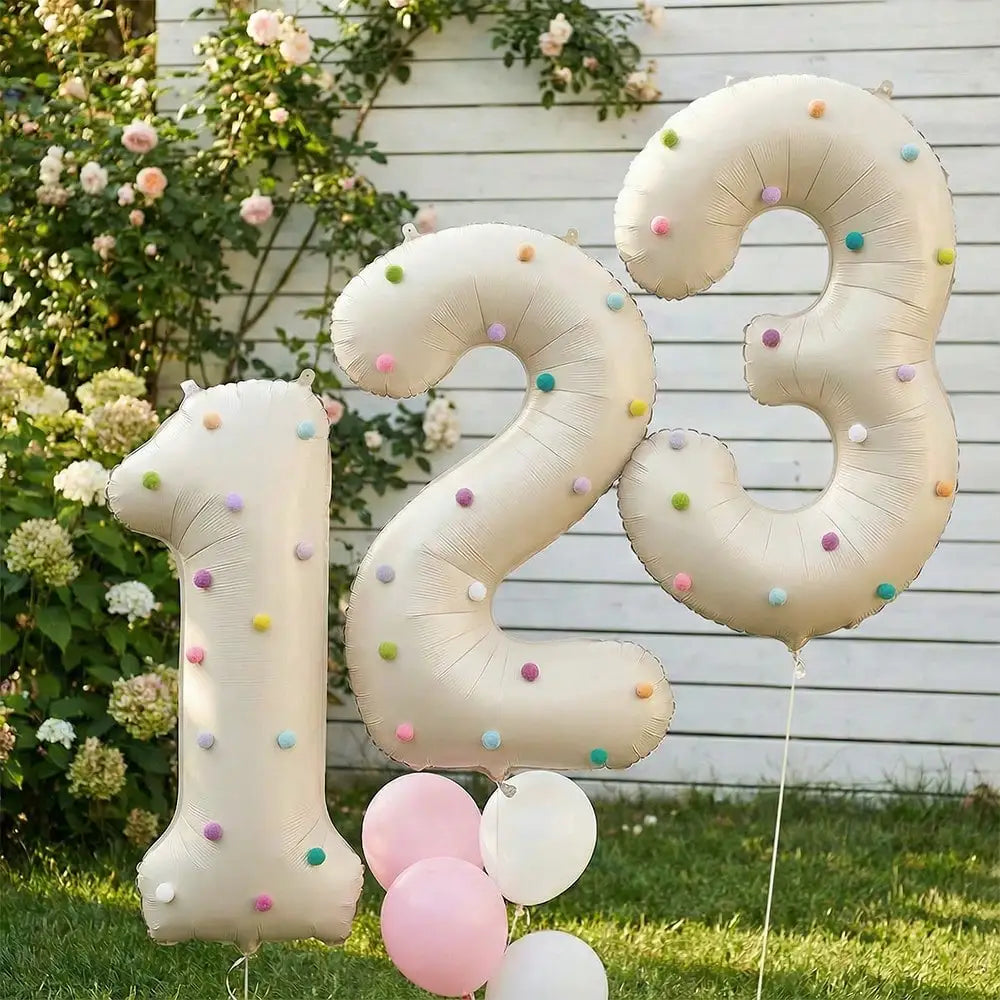 Large foil number balloons spelling out 123 in milky white and pastel colors against a green outdoor background