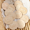 A collection of round wooden baby milestone cards showing numbers one through twelve for newborn keepsakes