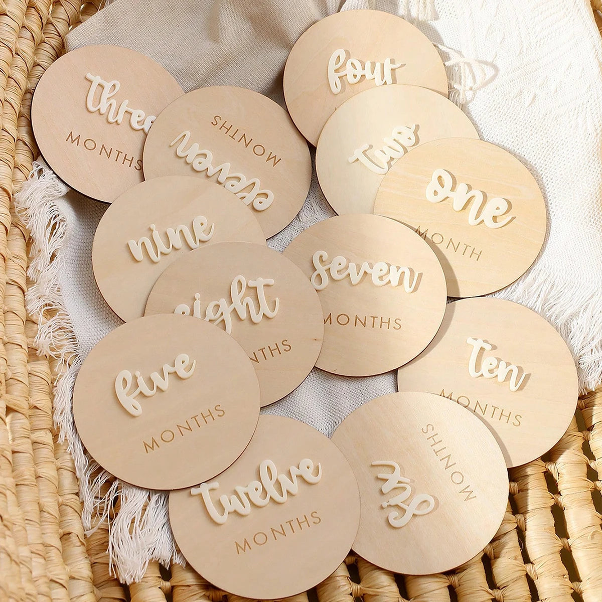 A collection of round wooden baby milestone cards showing numbers one through twelve for newborn keepsakes