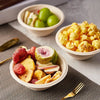 A serving of sliced apples and toast is presented alongside a bowl of scrambled eggs and a small bowl of green grapes.