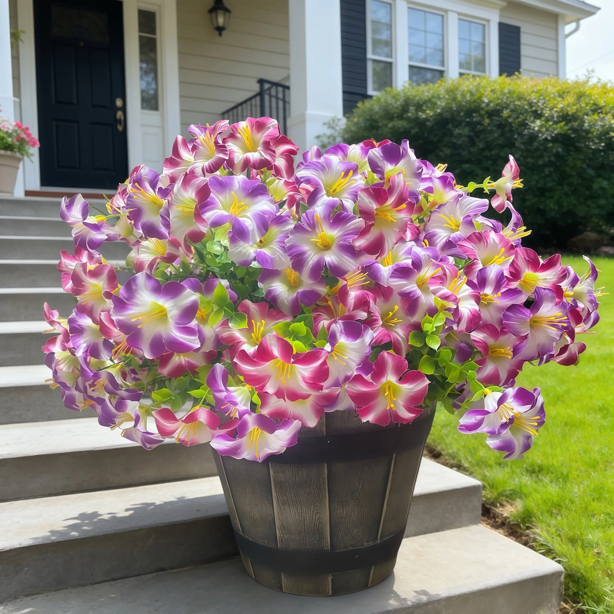 A vibrant bouquet of artificial silk flowers in shades of purple and pink sits in a dark planter on outdoor steps.