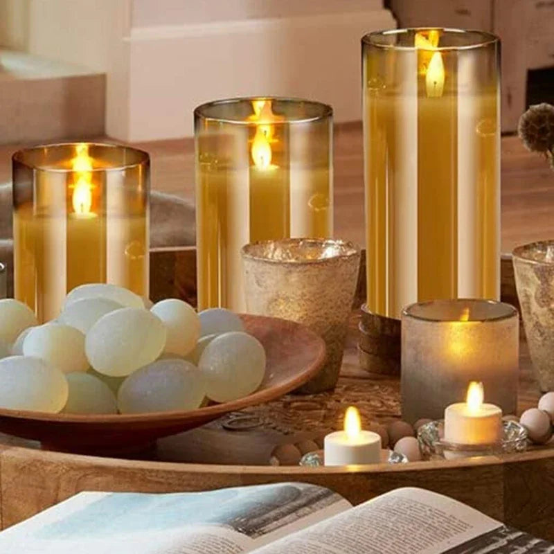 A collection of glowing amber glass pillar candles and small votives arranged on a wooden surface.