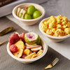 A close-up of a bowl filled with sliced fruit and a separate bowl containing yellow popcorn and green grapes.