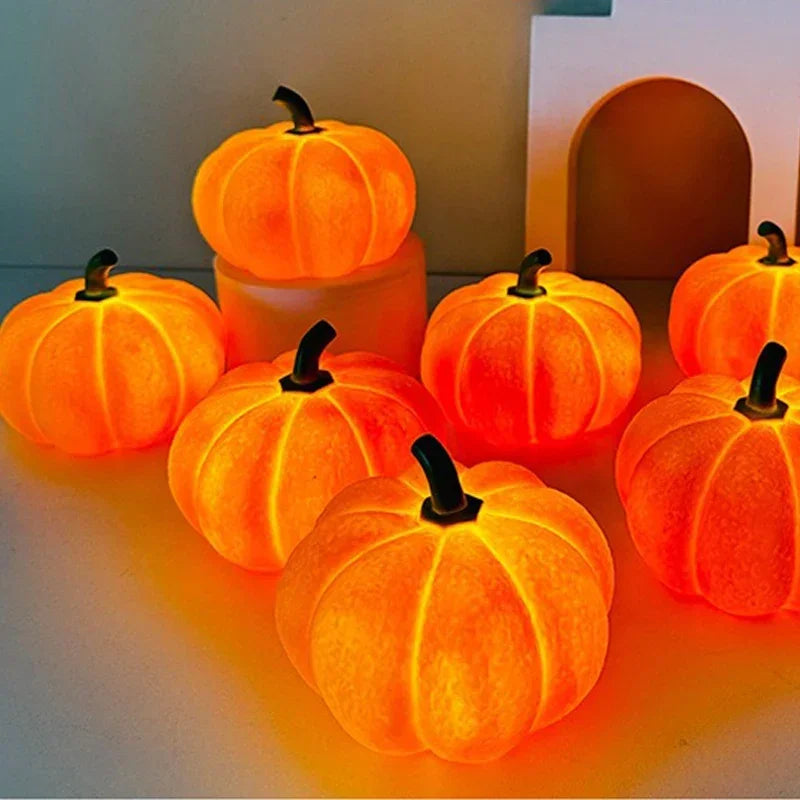 A collection of glowing orange decorative LED pumpkins arranged on a white surface.