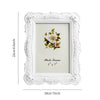 White ornate frame with a floral design and a photo insert