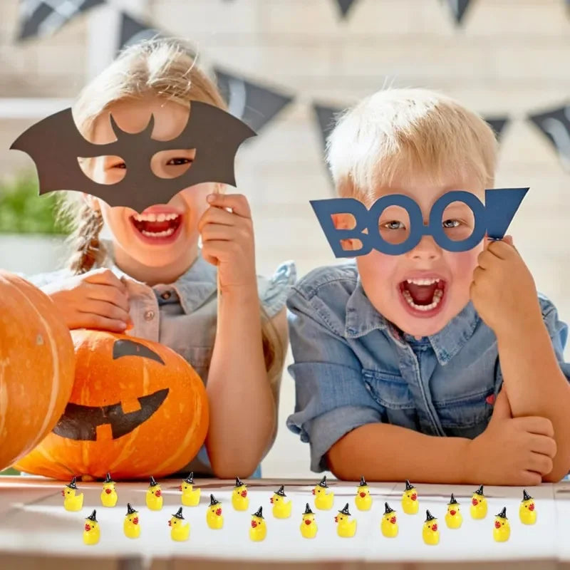 Two children make boo faces with black cutout bats and small yellow ducks for crafting