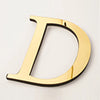 A shiny gold acrylic mirror letter D wall sticker for decorative purposes.