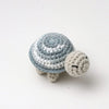 A handmade crocheted turtle plush toy with gray and white stripes resting on a white background.