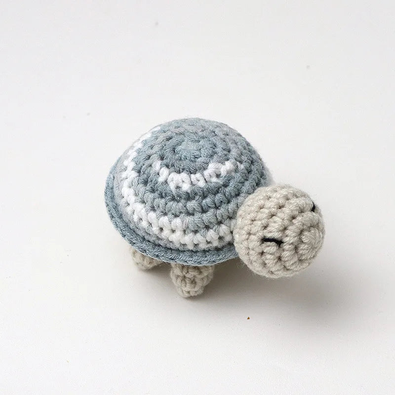 A handmade crocheted turtle plush toy with gray and white stripes resting on a white background.