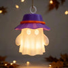 A purple camping ghost night light hangs, featuring a glowing white face and an orange brim.