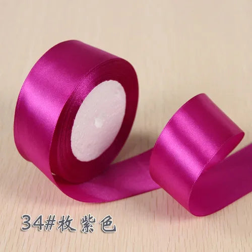 A roll of vibrant magenta silk satin ribbon used for gift wrapping and craft projects.