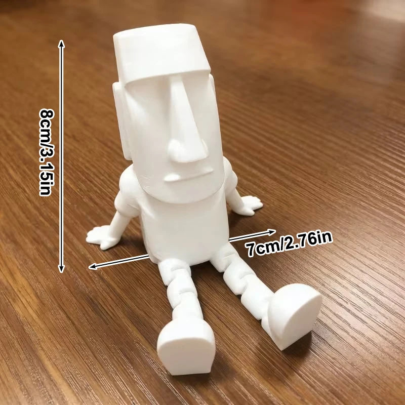 A white 3D printed Moai statue figurine with movable joints shown against a wooden background.