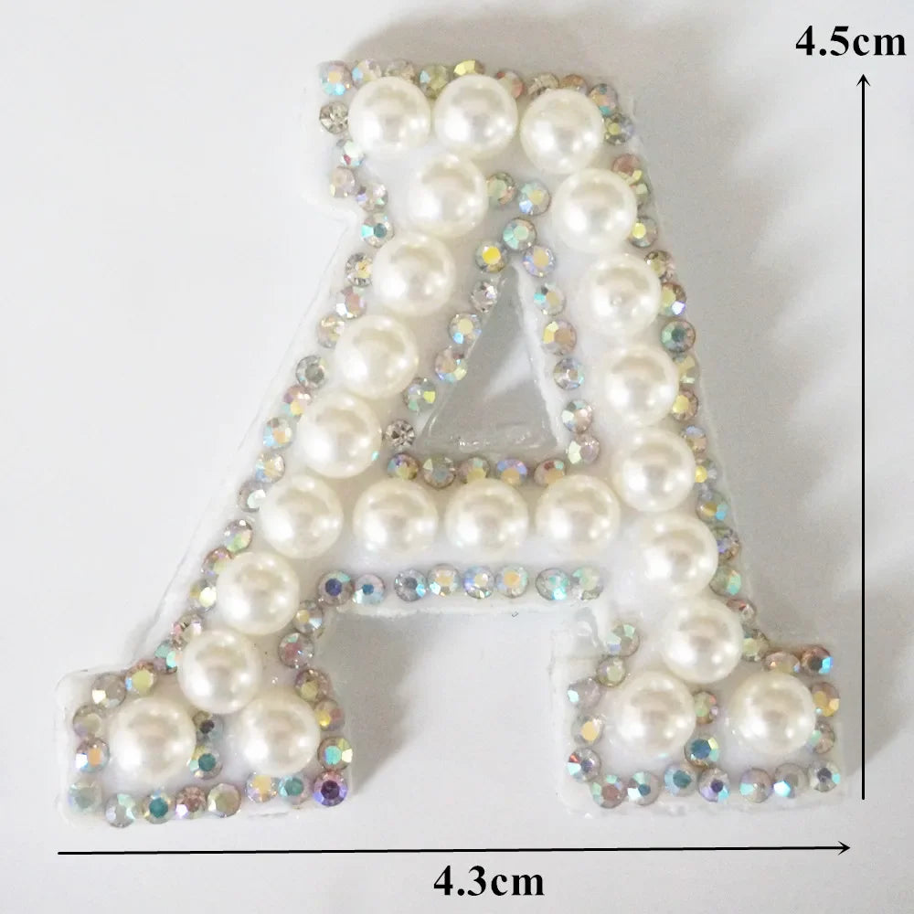 A alphabet letter patch made of white pearls and iridescent rhinestones