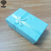 Una caja de regalo cuadrada azul claro atada con una cinta plateada, sobre una superficie de madera.