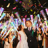 A woman in a white dress is being showered with light from LED fiber optic glow wands during a festive event.