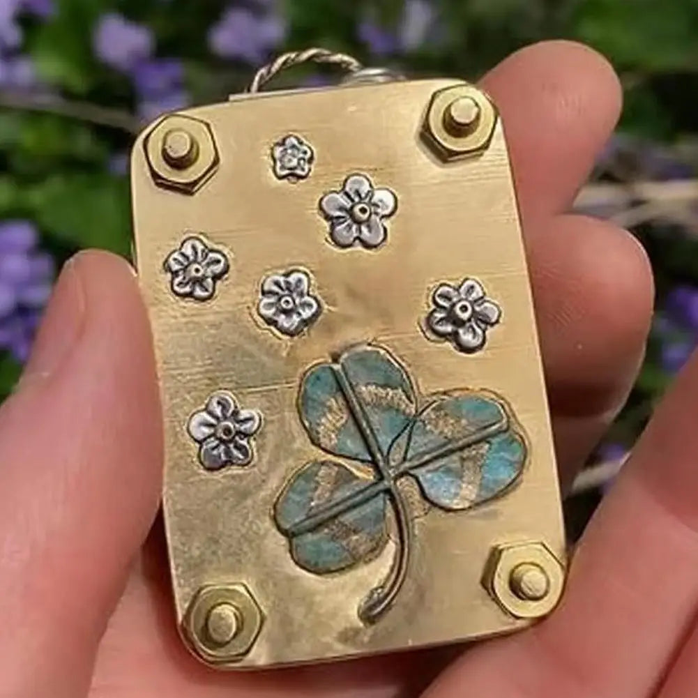 A small gold-toned metal press kit featuring embossed flowers and a large dried green and blue shamrock.