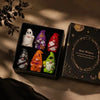 A set of seven Halloween witch mini dwarf resin figurines in various colors displayed in a black box.