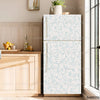A white refrigerator with a light blue floral pattern is displayed next to a wooden cabinet and a window.