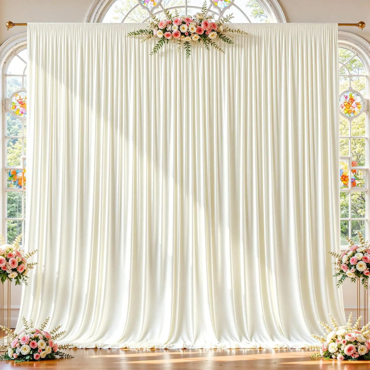 A white fabric backdrop with vertical pleats and floral greenery hangs between arched windows.