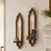A rustic wooden wall shelf with an arched design holds two lit candles and a small decorative item.