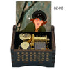 A hand-cranked wooden music box featuring a painted woman and brass components.