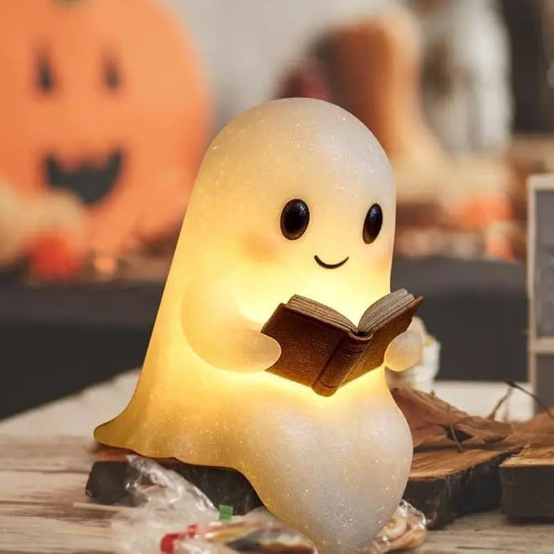 A cute ghost figurine lamp with a warm glow is shown resting on a wooden surface.