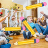 Niños sosteniendo globos de lápices inflables gigantes en una actividad de decoración divertida para escuela o graduación.
