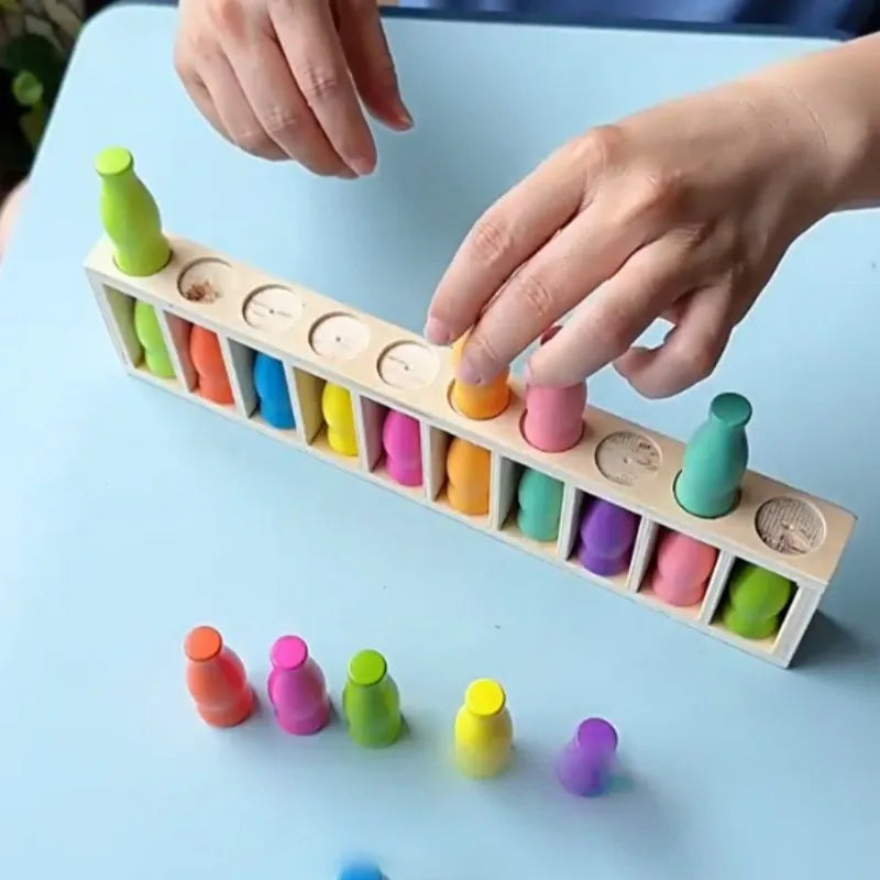 Hands are placing colorful plastic bottles into a wooden board for a matching game.